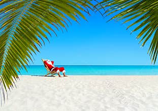 Christmas Santa Claus relaxing on sunlounger at ocean sandy tropical beach