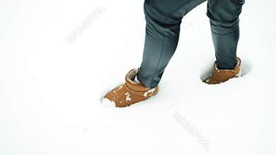 Female legs in brown uggs leave traces in the white pure snow.