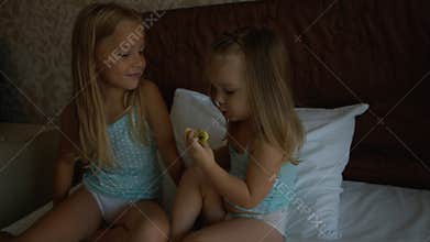 Two sisters sitting on the bed and eating apple