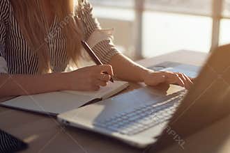Woman freelancer female hands with pen writing on notebook at home or office