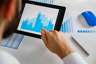 Business person analyzing financial statistics displayed on the tablet screen