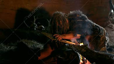 Caveman prepares a spear for hunting in his cave