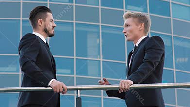 Two handsome smart business men having a conversation on terrace of office building