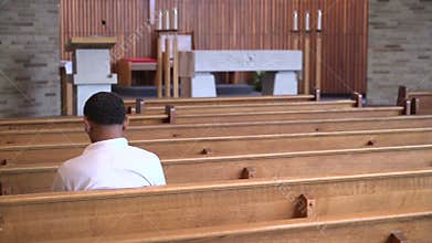 Sad man sits alone praying in a church