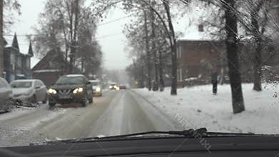 Bad driving conditions on city street. Bicyclist and cars on snowy frozen road