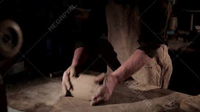 Adult male potter master preparing the clay on table. Front view, closeup, hands only, unrecognizable.