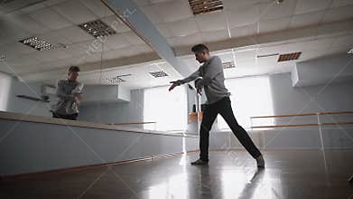 Young student of dancing school spinning and dancing near the mirror. Beautiful dancing man is showing passion and love