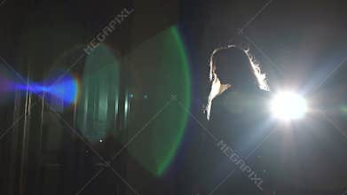 The silhouette of a gorgeous girl with light fluttering hair in the dark.