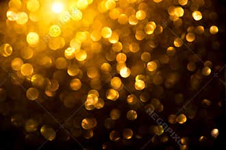 Christmas golden glowing background. Holiday abstract defocused backdrop. Tinsel blurred gold bokeh on black