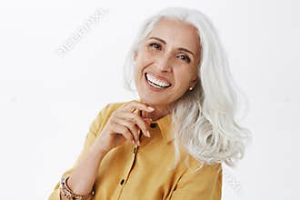 Close-up shot of happy delighted and accomplished charming european elderly female with white hair in yellow trench coat