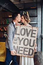 Loving couple kissing holding signboard all you need is love.
