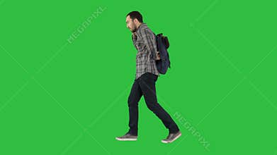 Young male student walking on isolated green background with bag and mobile phone on a Green Screen, Chroma Key.