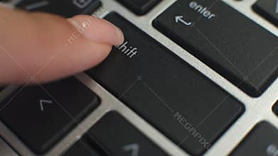 Woman pressing modifier shift button on laptop keyboard to type capital letters