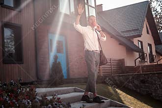 Pleasant friendly man greeting his neighbor while leaving home in the morning
