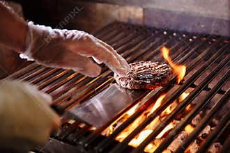 Chef making burger. Beef or pork meat barbecue burgers for hamburger prepared grilled on bbq fire flame grill. Close-up
