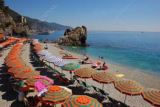 Summer Holiday on Italian Riviera with bright orange green umbrella at Liguria region, Italy