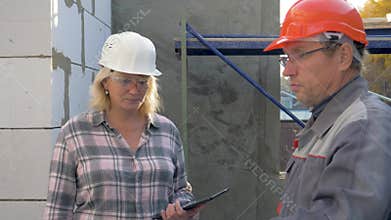 Builder and customer inspect the building under construction inside in rooms