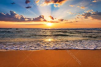 Colorful ocean beach sunrise with deep blue sky and sun rays