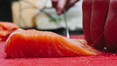 Chef takes out bones from the salmon fillet, cutting fish on slices for cooking sushi in 4k resolution in slow motion