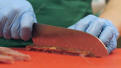 Hands of cook using knife for cutting jerky meat while cooking in restaurant