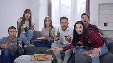 Sport fans watching decisive moment of game and happy for victory sitting on the sofa in front of TV eating pizza and