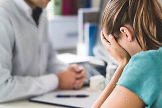 Sad patient visiting doctor. Young woman with stress or burnout getting help from medical professional or therapist.
