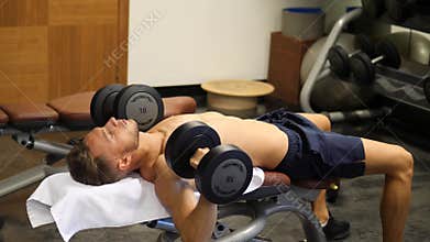 Handsome young man exercising biceps in gym