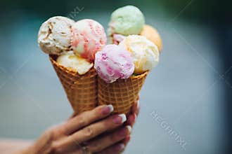 Crop of woman`s hand holding delicious colorful ice cream.