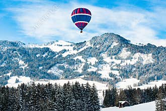 Hot-air balloon over snow covered landscape in Pre-Alps, Bavaria, Germany