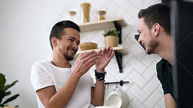Close up of gay couple are sitting behind kitchen table and having breakfast in the morning at kitchen. Handsome young