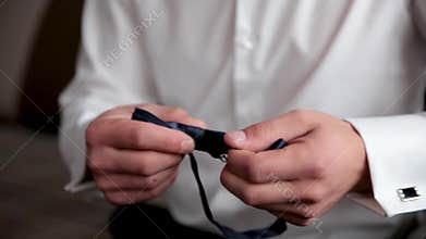 Businessman putting on bow tie,man butterfly clothes,groom getting ready in the morning before wedding ceremony. Men