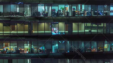 Working evening in glass office building with numerous offices with glass walls and windows timelapse