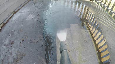 Man cleaning terrace with a power washer - high water pressure cleaner on wooden terrace railing