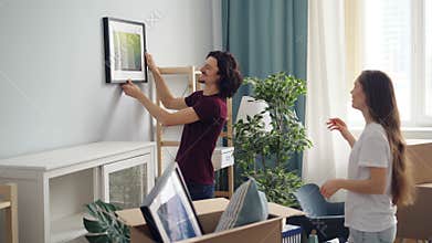 Happy people decorating flat with picture choosing place talking and gesturing
