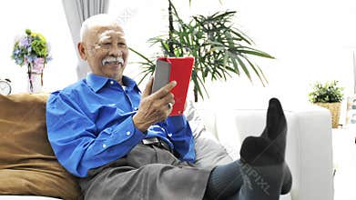Asian senior man with white mustache using tablet computer at home,