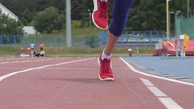 Young beautiful woman athlete starts running at athletics track during a day training in slow motion 4K video on UHD
