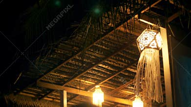 Atmospheric background shot of beautiful string lights at night terrace, traditional paper lantern waving in the wind.