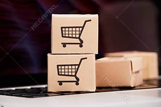 Online shopping . ecommerce and delivery service concept : Paper cartons with a cart or trolley logo on a laptop