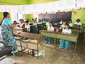 Group of children friends classmates studying with book sitting on chairs indoors at the school. School kids enjoying friendship
