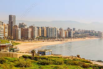 Downtown buildings and towers with road, sandy beach and sea in the foreground, Beirut, Lebanon