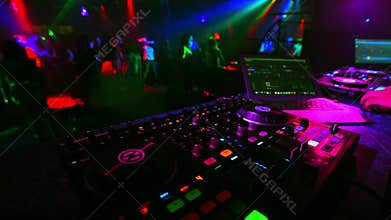 Blurred dancing crowd of people in a nightclub at party with a DJ music mixer