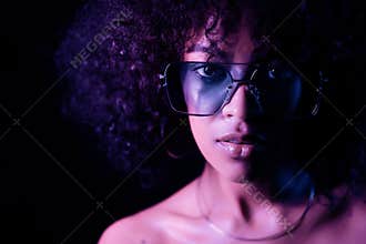 Portrait of young alluring mixed race girl in neon light. Fashion, glamour, model concept. Seductive woman with make-up