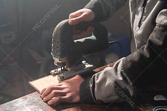 Close up of carpenter`s hands working power tools for processing wood. Power Jigsaw