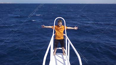 Adorable boy standing on the yacht bow