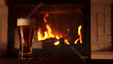 Panning shot full glass of appetizing cooled refreshment beer with foam surrounded by fireplace