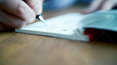 Woman filling a cheque book with fountain pen euro sign signature
