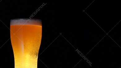 Medium shot stream of fresh cold beer beverage pouring into full big glass slowmo