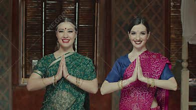 Pretty women connecting hands in namaste greeting