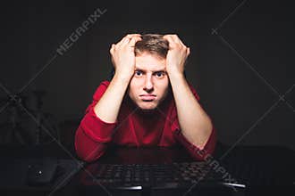 Portrait of a frustrated gamer looking at a computer monitor with a sad faces expression