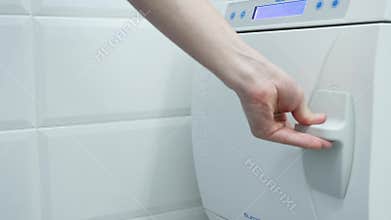 Hands are putting sets of dental instruments into autoclave for sterilization